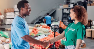 Shaking hands, welcome and volunteers for donation at food drive, charity or non profit organizatio