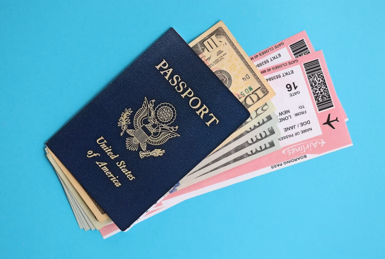 Blue United States of America passport with money and airline tickets on blue background
