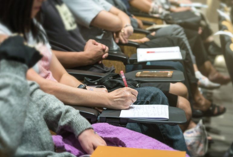 Close up shot of woman hand writing on the paper at the table in the conference hall