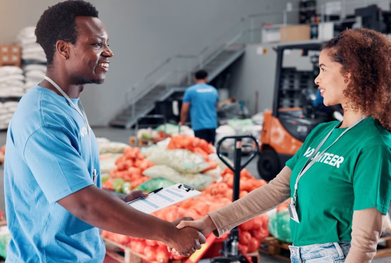 Shaking hands, welcome and volunteers for donation at food drive, charity or non profit organizatio